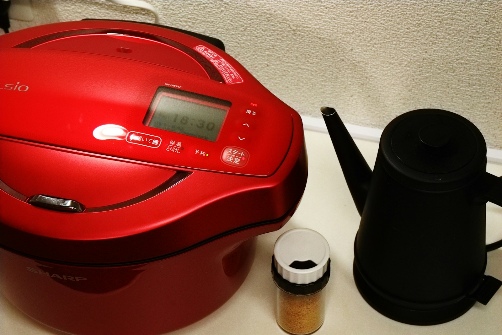 Rice cooker listrik merah di atas meja dapur